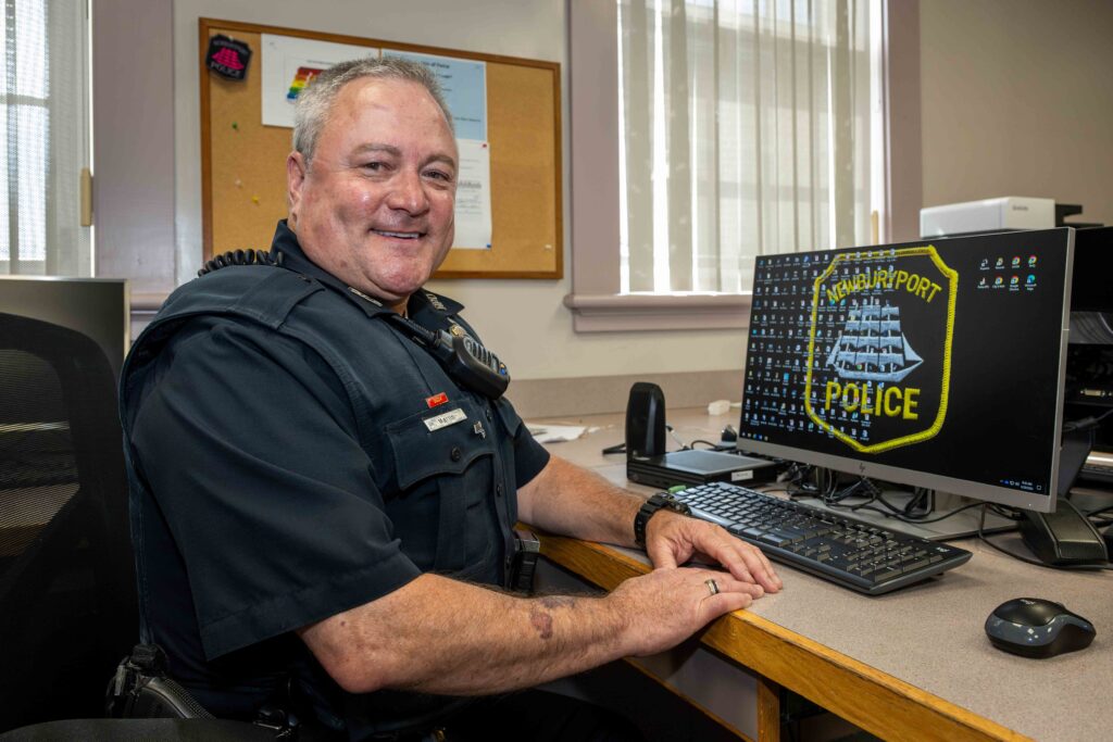 An older male police officer sitting at his desk.